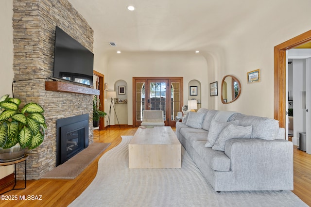 living room with baseboards, recessed lighting, a stone fireplace, and wood finished floors
