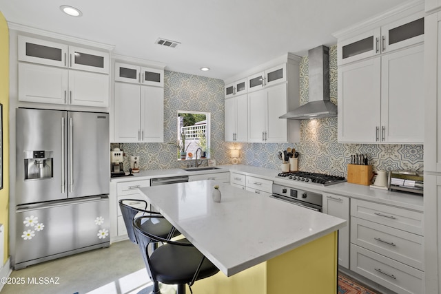 kitchen featuring visible vents, appliances with stainless steel finishes, tasteful backsplash, a sink, and wall chimney exhaust hood