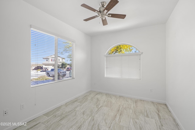 empty room featuring a ceiling fan and baseboards