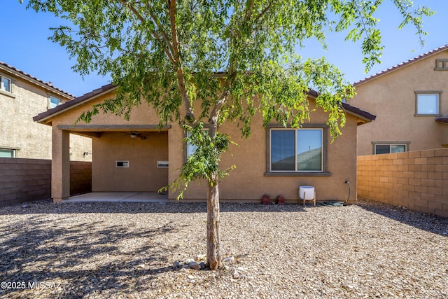 back of property featuring fence, ceiling fan, stucco siding, and a patio area