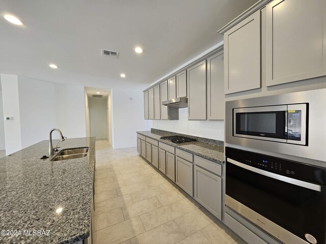 kitchen featuring stainless steel appliances, gray cabinetry, visible vents, and a sink