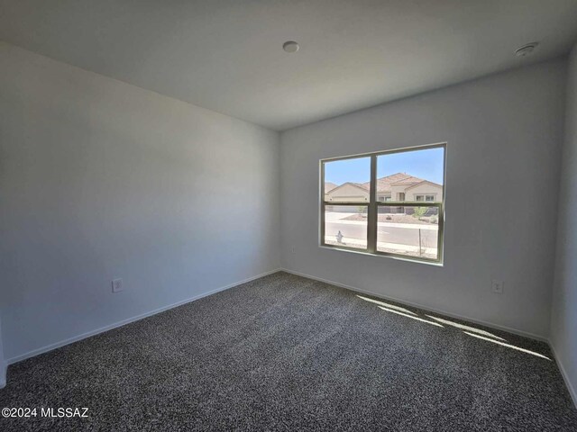 spare room with baseboards and carpet flooring