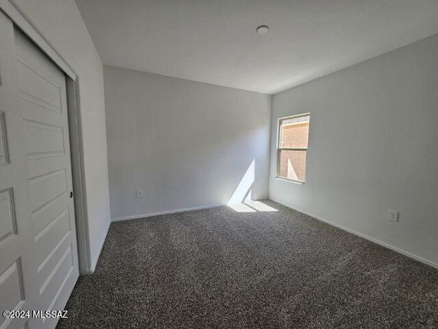 carpeted empty room featuring baseboards