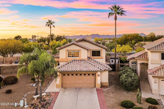 mediterranean / spanish-style home featuring a tiled roof, driveway, and stucco siding