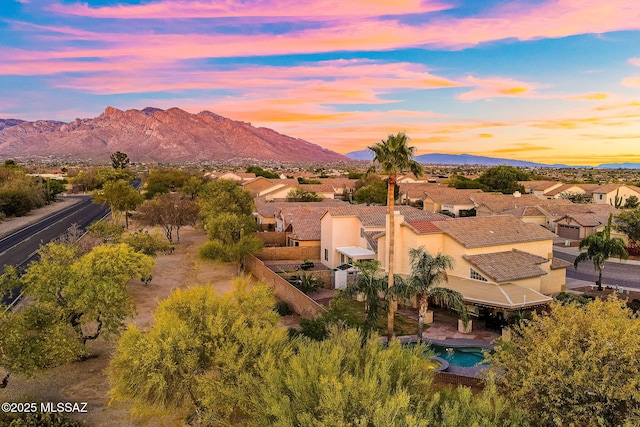 aerial view at dusk featuring a mountain view and a residential view