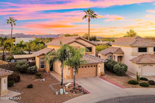 mediterranean / spanish-style home featuring an attached garage, a tile roof, stucco siding, a mountain view, and concrete driveway