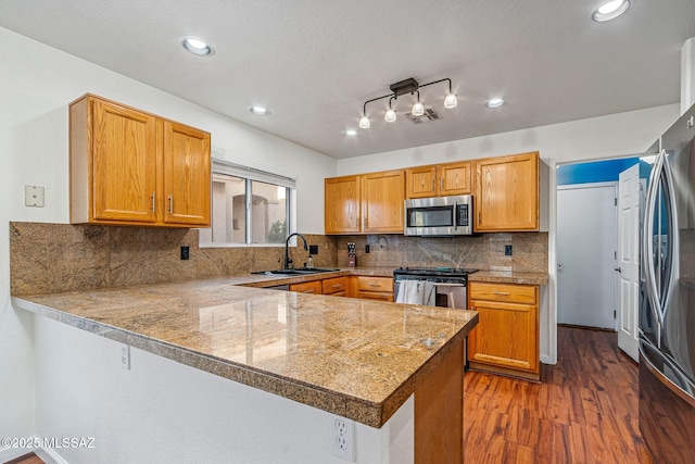 kitchen with dark wood-style flooring, a sink, stainless steel appliances, a peninsula, and visible vents
