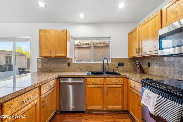 kitchen featuring appliances with stainless steel finishes, a sink, tile countertops, decorative backsplash, and dark wood-style floors