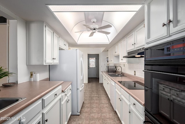 kitchen featuring white cabinets, a sink, a ceiling fan, under cabinet range hood, and black appliances