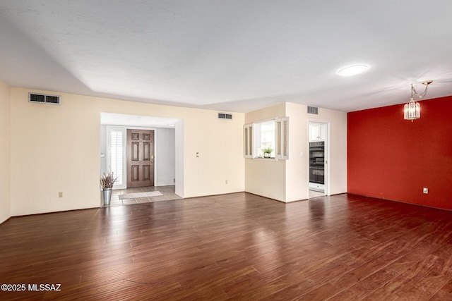 unfurnished living room featuring visible vents, plenty of natural light, and wood finished floors