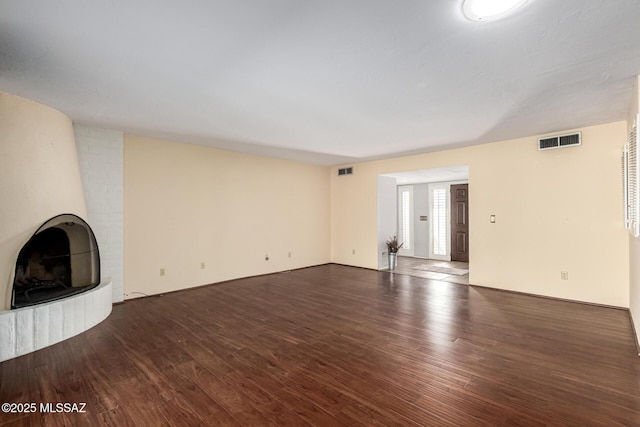 unfurnished living room featuring wood finished floors and visible vents