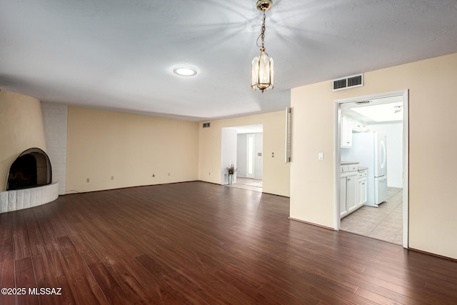 unfurnished living room with a fireplace, wood finished floors, and visible vents