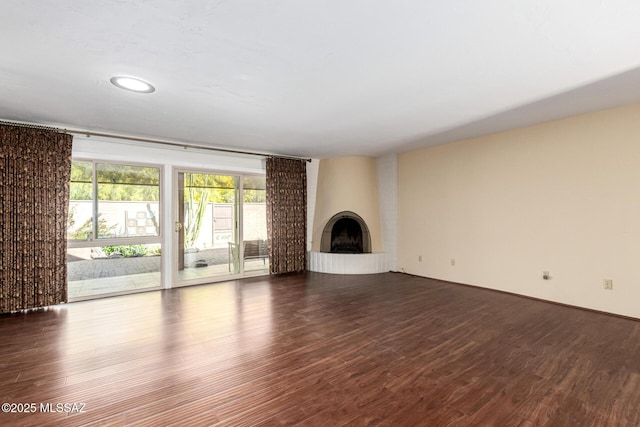unfurnished living room featuring dark wood-type flooring and a fireplace