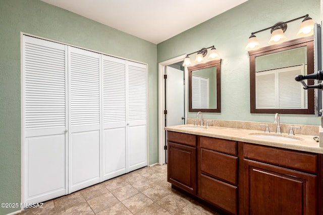 bathroom featuring double vanity, tile patterned floors, a sink, and a closet