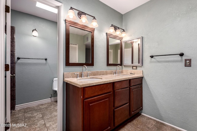 full bathroom with double vanity, toilet, a sink, and tile patterned flooring