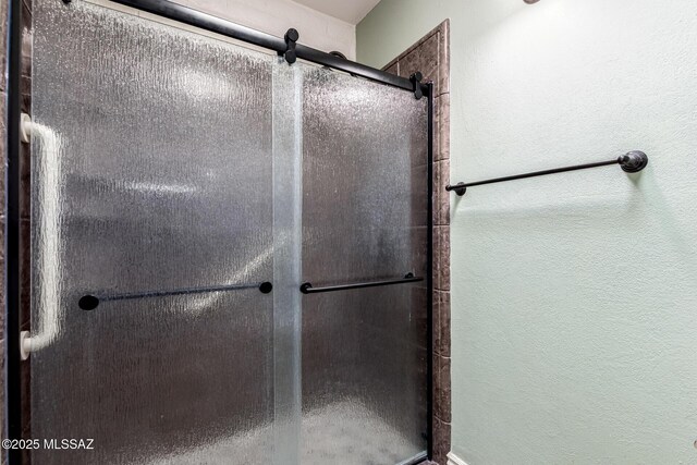 full bath with a textured wall and a stall shower
