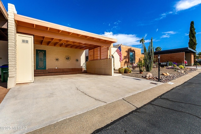 view of front of property featuring entry steps, a carport, and driveway