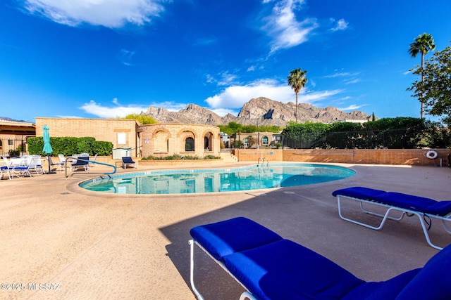 pool featuring fence, a mountain view, and a patio area