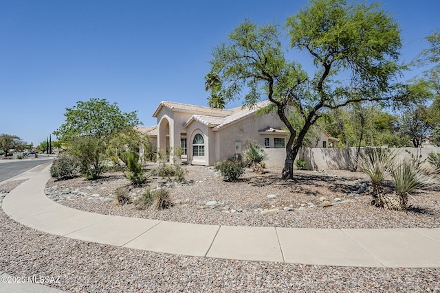 view of property exterior with fence, stucco siding, and a tiled roof