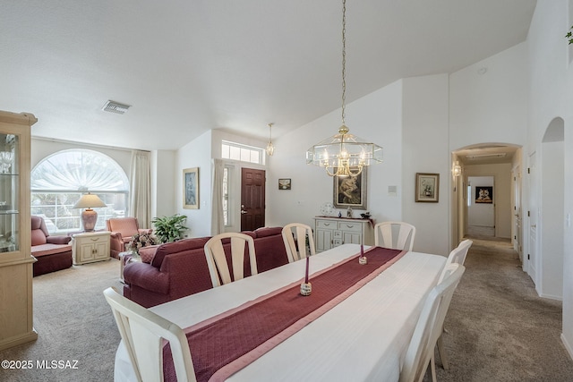 dining space with visible vents, arched walkways, a notable chandelier, and light carpet