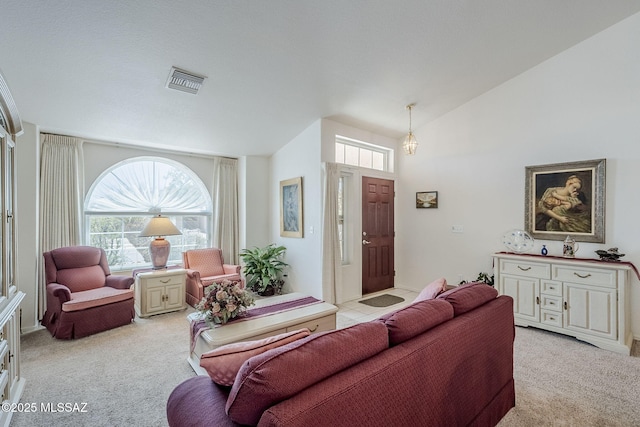 living area with vaulted ceiling, light carpet, and visible vents