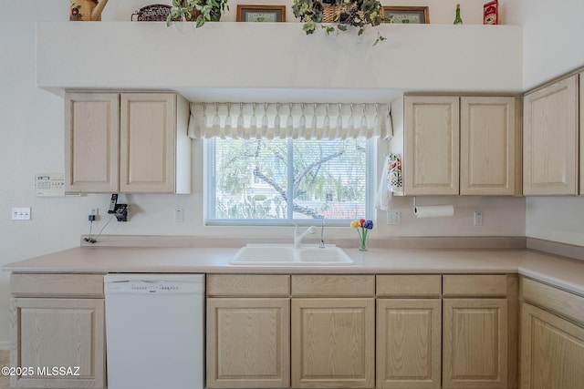 kitchen featuring white dishwasher, a sink, light brown cabinets, and light countertops