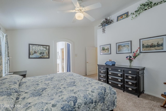 bedroom featuring arched walkways, a ceiling fan, vaulted ceiling, and light carpet