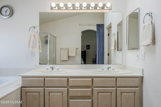 bathroom with double vanity, a sink, a bath, and a stall shower