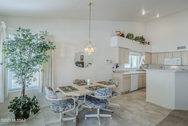 dining space with visible vents, baseboards, a towering ceiling, and an inviting chandelier