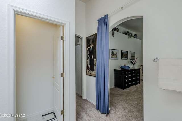 hall with carpet floors, arched walkways, and baseboards