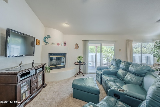 living area featuring carpet floors, visible vents, a glass covered fireplace, recessed lighting, and vaulted ceiling
