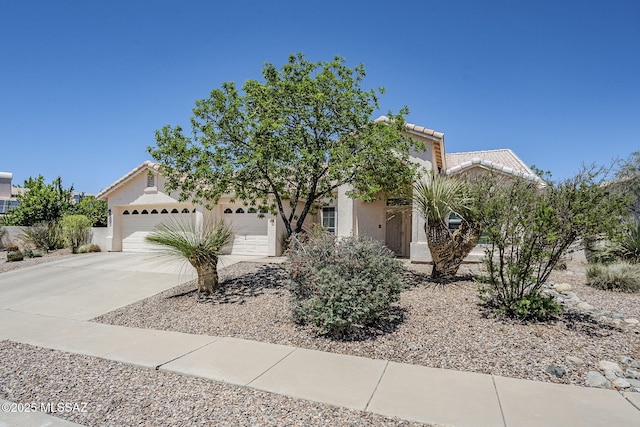view of property hidden behind natural elements featuring a garage, stucco siding, driveway, and a tiled roof
