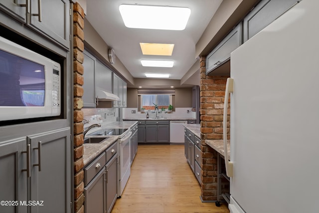 3202 W Calle Cereza, Tucson, AZ 85741 - kitchen featuring under cabinet range hood, tasteful backsplash, light wood-style flooring, white appliances, and gray cabinetry