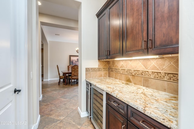 36330 S Desert Sun Dr, Tucson, AZ 85739 - kitchen featuring beverage cooler, baseboards, light stone counters, tasteful backsplash, and dark brown cabinetry