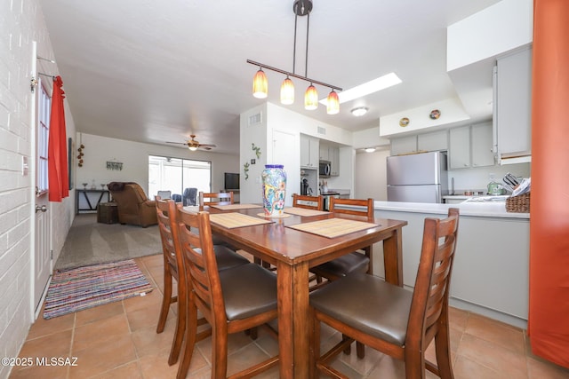dining area with visible vents, a ceiling fan, light tile patterned flooring, and a skylight