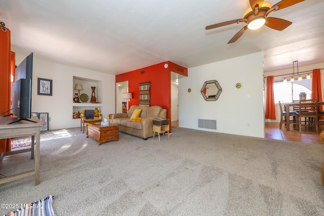 living area featuring carpet floors, a ceiling fan, and visible vents