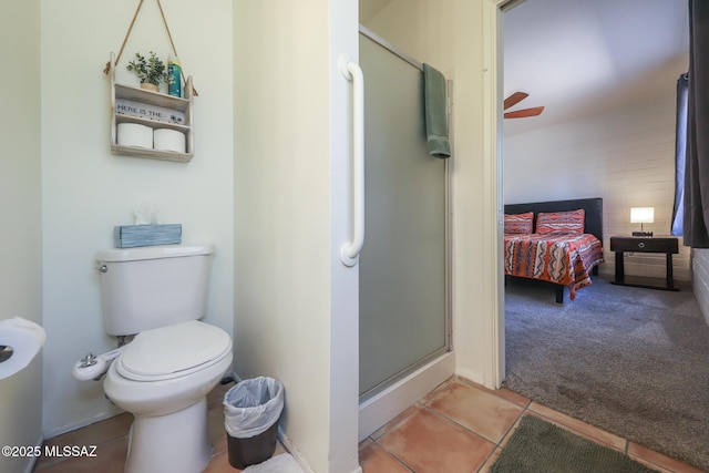 ensuite bathroom featuring a ceiling fan, a shower stall, tile patterned floors, toilet, and ensuite bathroom