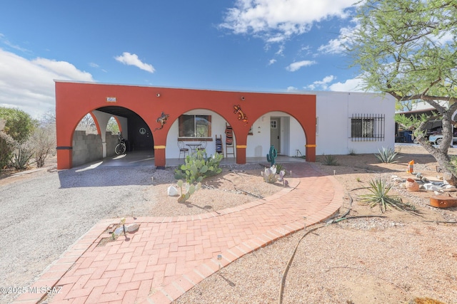 view of front of home featuring stucco siding and gravel driveway