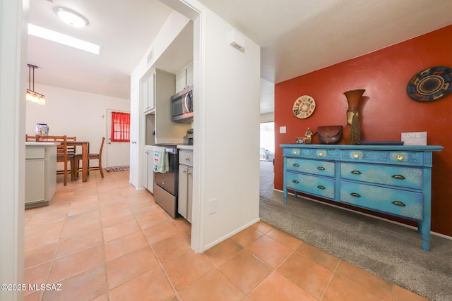 kitchen featuring baseboards, electric range, stainless steel microwave, and light tile patterned floors