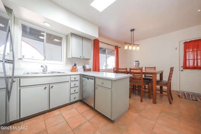 kitchen featuring a sink, light countertops, a peninsula, stainless steel dishwasher, and pendant lighting