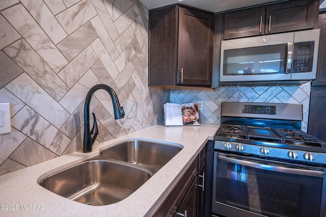 kitchen featuring dark brown cabinets, a sink, light stone countertops, decorative backsplash, and appliances with stainless steel finishes