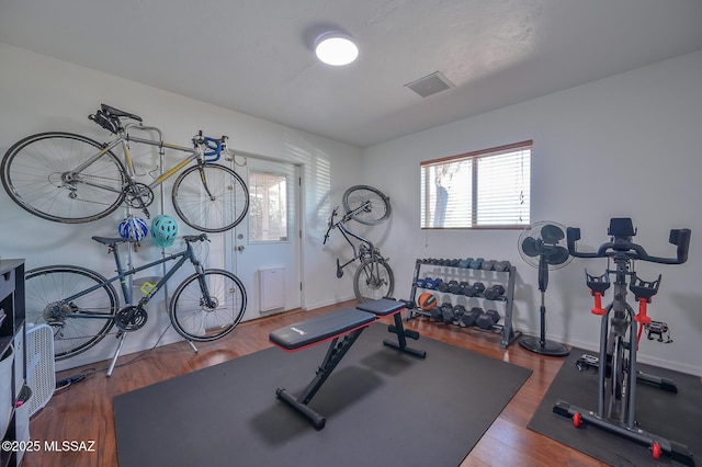 exercise area featuring a healthy amount of sunlight, wood finished floors, and visible vents