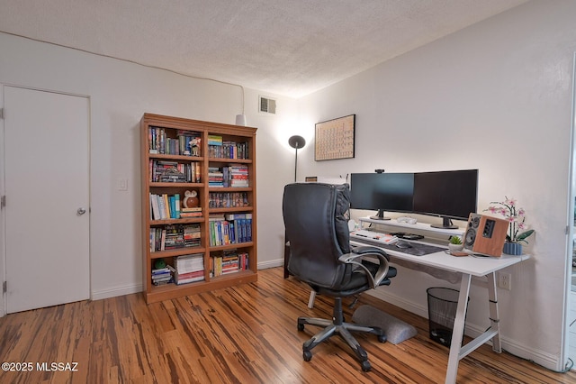 office area featuring a textured ceiling, wood finished floors, visible vents, and baseboards