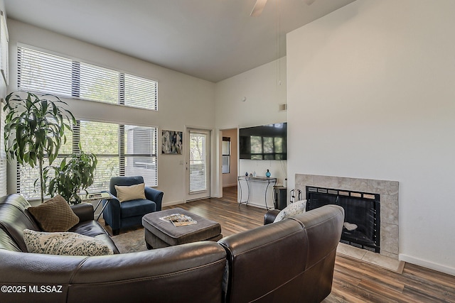 living area featuring a premium fireplace, a high ceiling, baseboards, and wood finished floors
