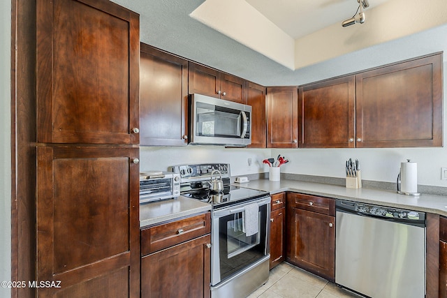 kitchen featuring light tile patterned floors, light countertops, stainless steel appliances, and a toaster