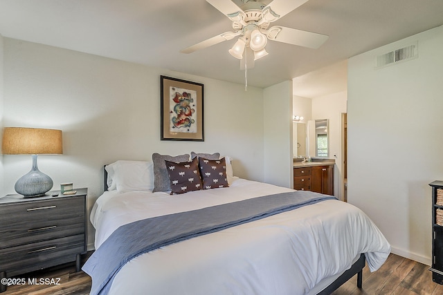bedroom featuring ceiling fan, visible vents, dark wood finished floors, baseboards, and connected bathroom