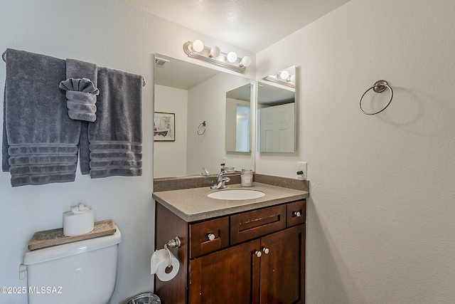 half bathroom with vanity, toilet, and visible vents