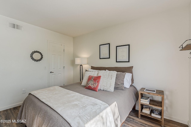 bedroom with baseboards, visible vents, and wood finished floors