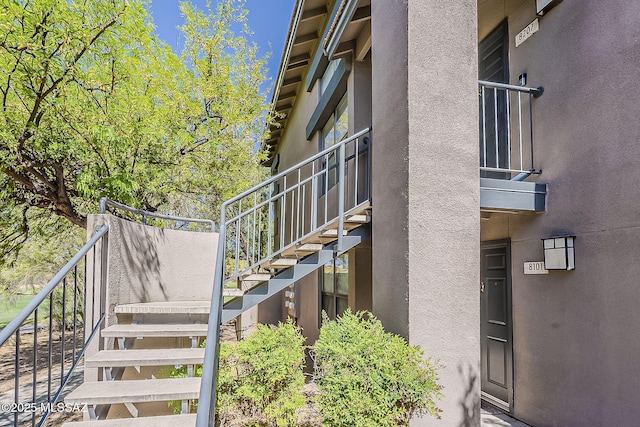 view of side of home with stairs and stucco siding