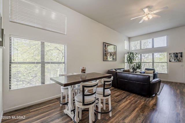 dining room with dark wood-type flooring, a ceiling fan, and baseboards